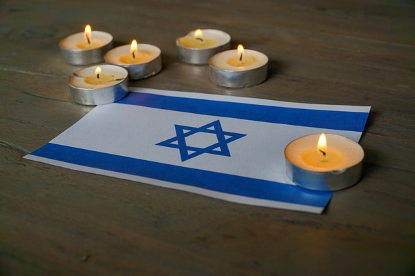 An,Israeli,Flag,,Bathed,In,Candlelight,,Casts,A,Somber,Reflection